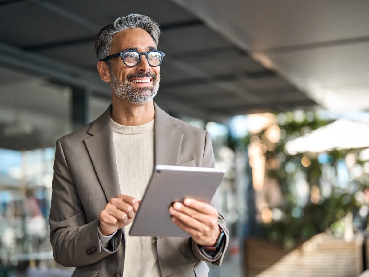 A smiling professional with a tablet, reviewing his own version of the product